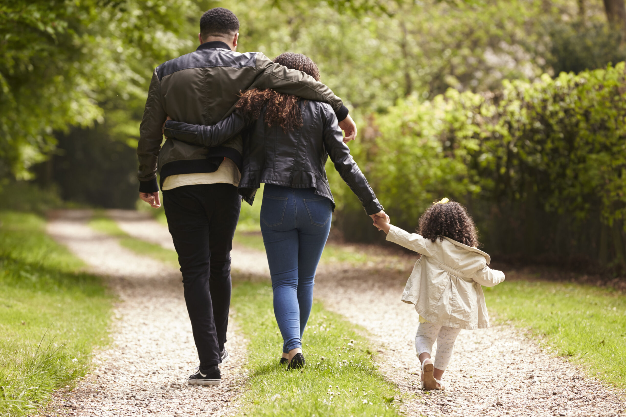 Couple with young daughter on a country walk, back view